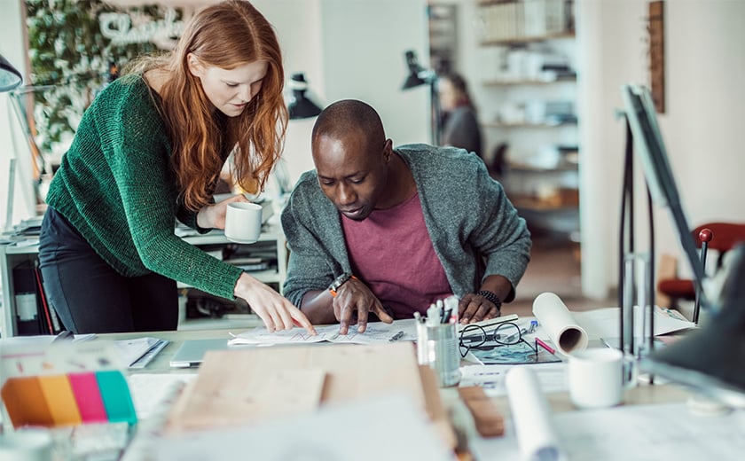 Man and woman at a desk, carefully examining a piece of paper