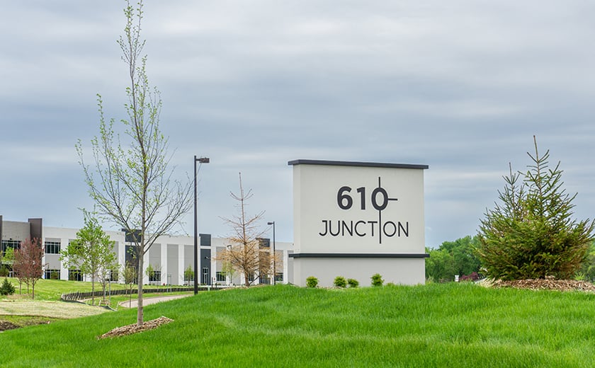 610 Junction monument sign on a grassy hill in front of a building 