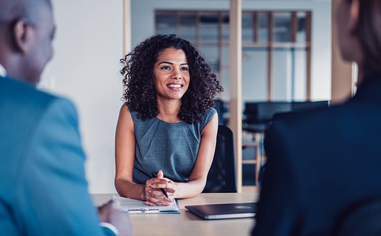 A woman sitting in a meeting with her hands folded