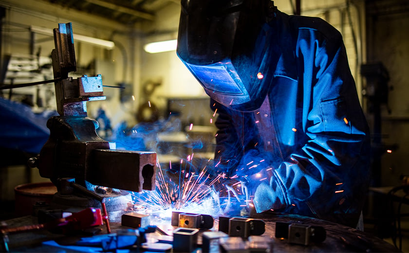 Welder in mask constructing a sign with sparks flying 