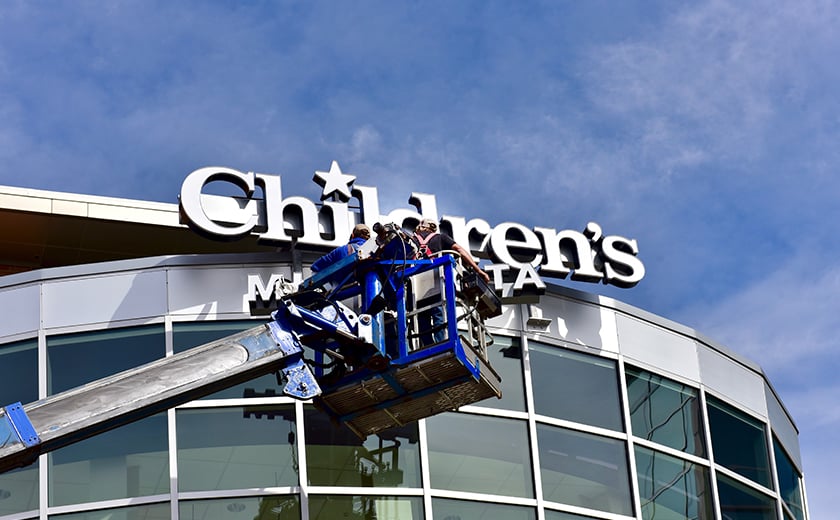 Crane with sign installers outside of Children's Mercy hospital 