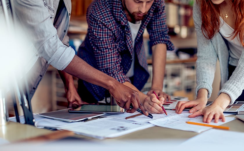 Group of people pointing and working on a sketch design 